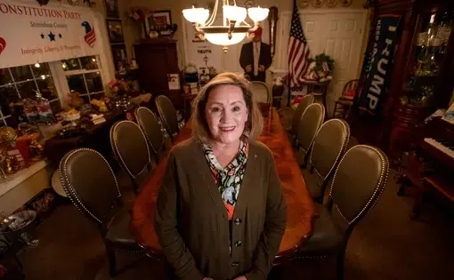 woman stands surrounded by Trump stuff