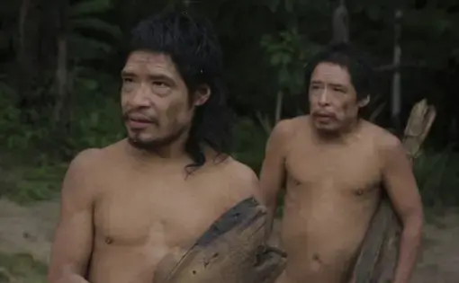 Two people pose for the camera. The person on the right is carrying a stick.