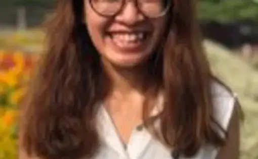 A woman with glasses and wearing a white shirt smiles into the camera.