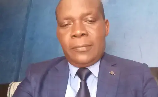 A man wears a black tie, blue shirt and a blue jacket.