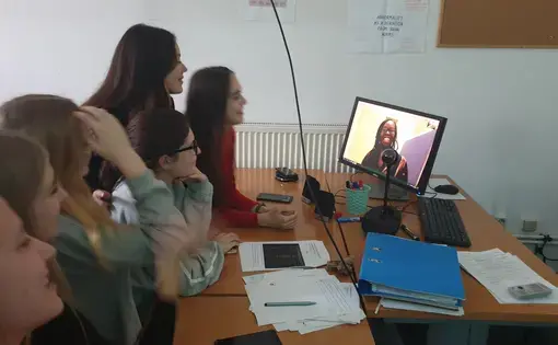 Students gather around a computer to listen to Erica Ayisi present.