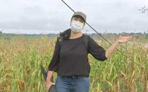 A person wears a black shirt and blue jeans. The person points with their right hand and is talking.