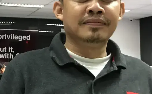 A person wears a black shirt with a red patch logo.