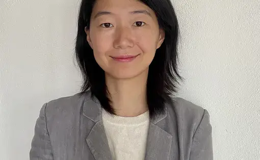 A person wears a grey jacket and a white shirt.