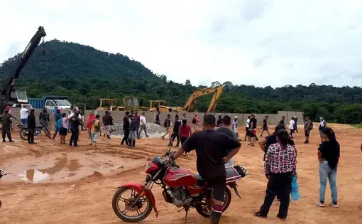 A crowd of people stand and look at the deforested mining area.