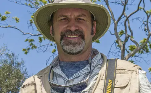 Man with a hat and a mustache looks into the camera