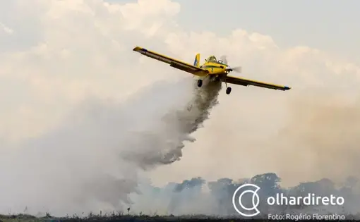 A yellow airplane drops water from the sky.