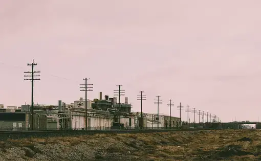 Electricity wires spread across a landscape with a pink sky