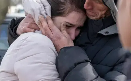 A father and teenage child in a teary embrace