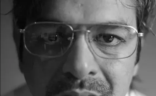 A person wears a shirt and glasses.