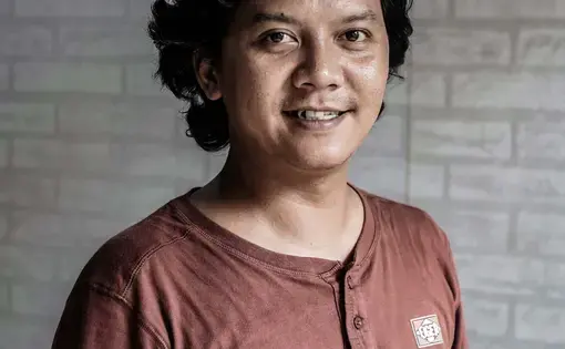 A person wears a red long-sleeve shirt with buttons.