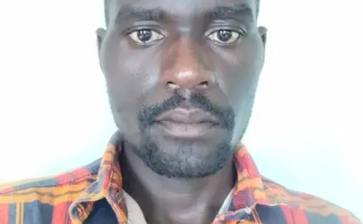 A man with an orange shirt stares into the camera