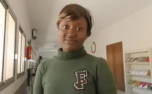 A woman with brown hair is wearing a dark green sweatshirt with the letter F.
