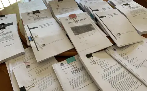 A pile of mining audit reports lay on a desk.