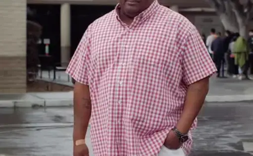 Travielle stands in a red shirt in a parking lot