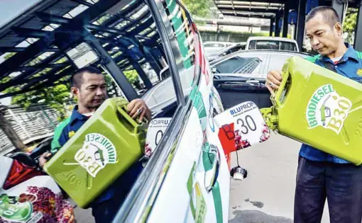 A man uses a green gasoline container to pour gas into his van.