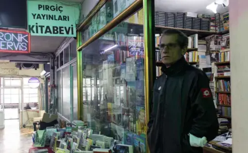 man stands in front of a bookstore