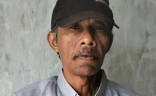 A man wears a cap and a blue shirt.