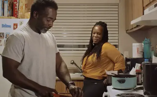 Man cuts in kitchen while his wife watches