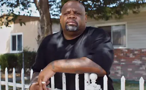 Man poses in front of fence