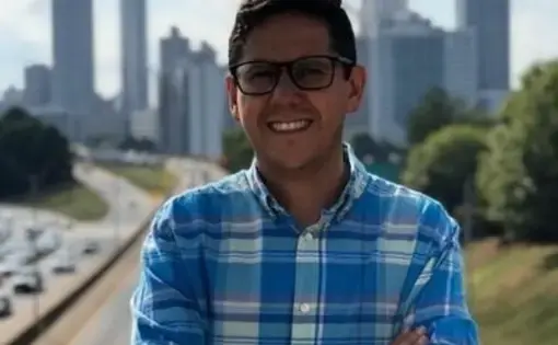 A man with eyeglasses and wears a blue-striped shirt.