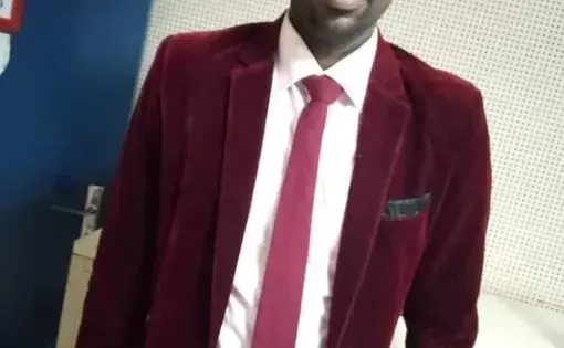 A man wearing a purple jacket and tie with a white work shirt.