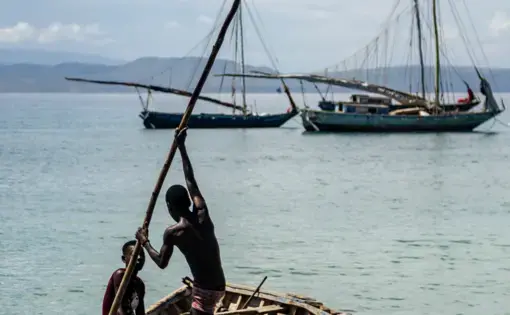 Young boys row a small boat in bright blue Caribbean waters