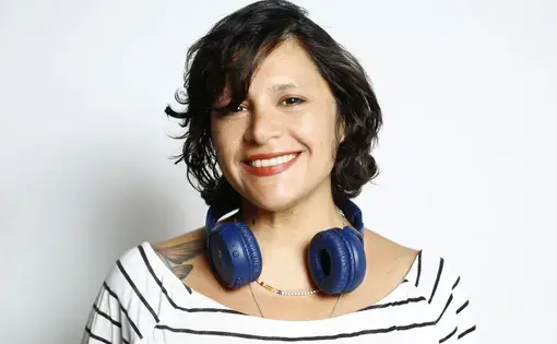 A woman with short hair, headphones, and wears a striped shirt.