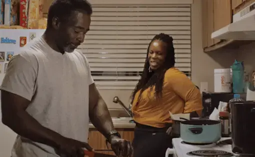 Man chops while wife leans against counter watching