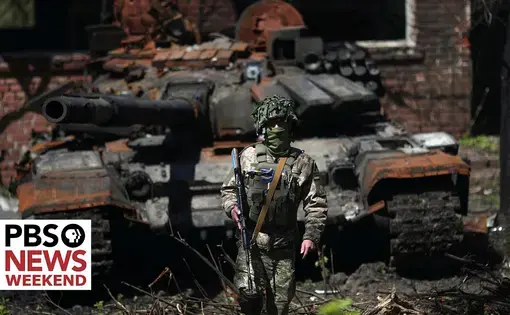 a masked soldier stands in front of a rusted tank