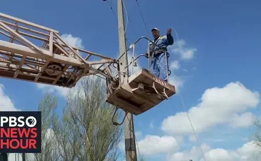 an energy worker on a cherry picker holds a piece of cord