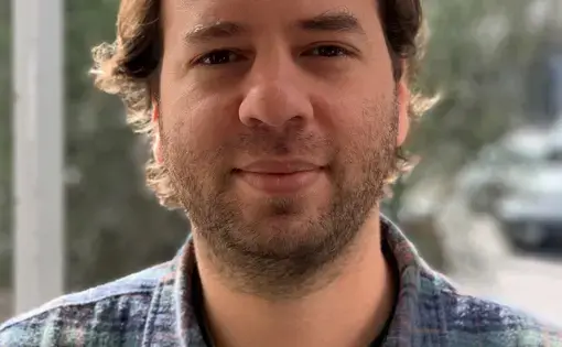 A man with facial hair and wears a striped shirt.