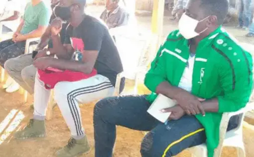 Men are sitting in plastic chairs as they listen to a lecture.