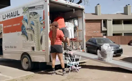 A woman loads a UHAUL truck.