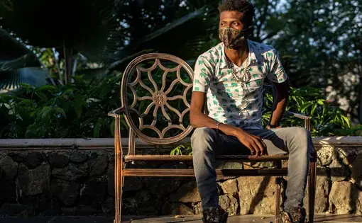 a masked man sits on an iron bench in a park