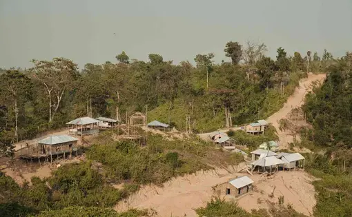 Stilted homes on a desiccated and sandy hill.