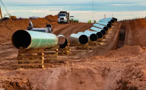 Shutterstock image; a truck comes over a hill lined with pieces of oil pipeline