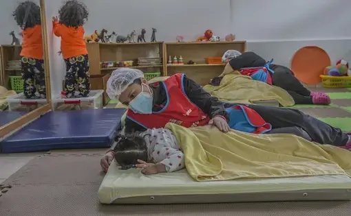 A childcare worker looks after a napping child.