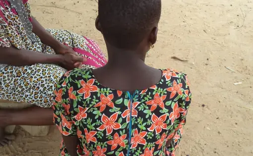 A young girl sits facing away from the camera