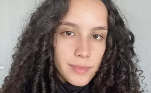 a woman with curly hair looks into the camera