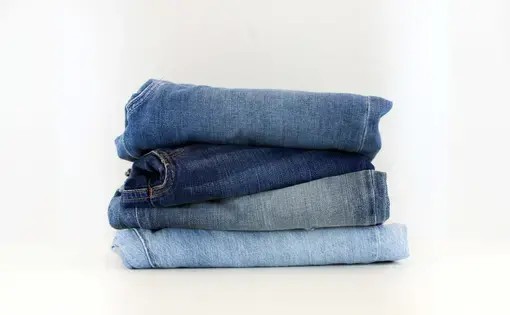 A stack of blue jeans from a light wash at the bottom to a dark at the top