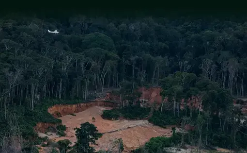 A small plane flies over a mining operation in the Amazon rainforest