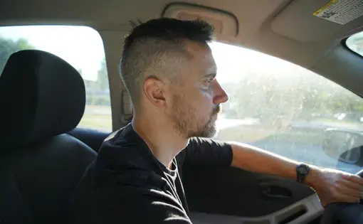 A man in the drivers seat looks towards the road