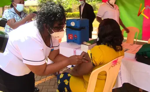 A nurse administers a vaccine into the arm of a patient.