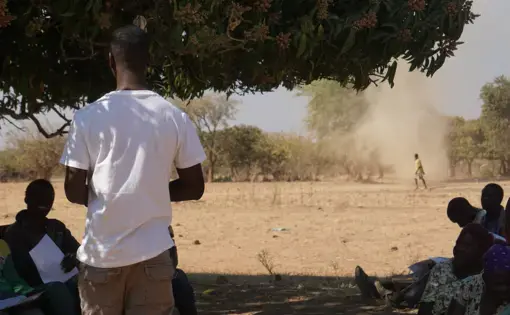 A whirlwind of sand spins past farmers
