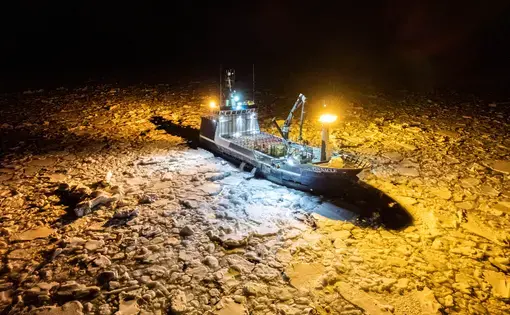 Boat cutting through warmly-lit ice at night.