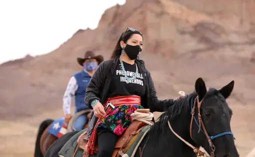 A woman on a horse with a mesa in the background.