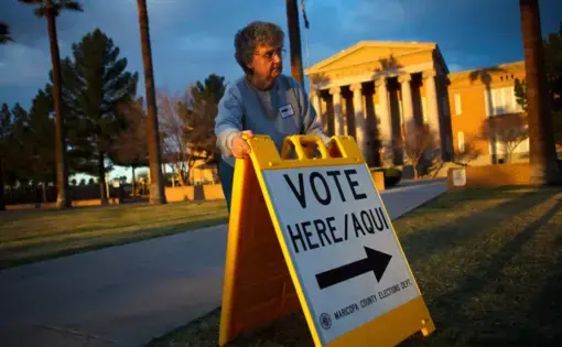 A person sets up a sign directing voters to a polling station at dawn