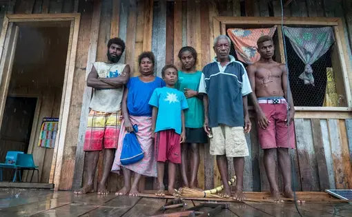 A family stands against the wall of a wooden structure.
