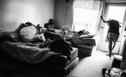 A person leaning on door in a motel room.